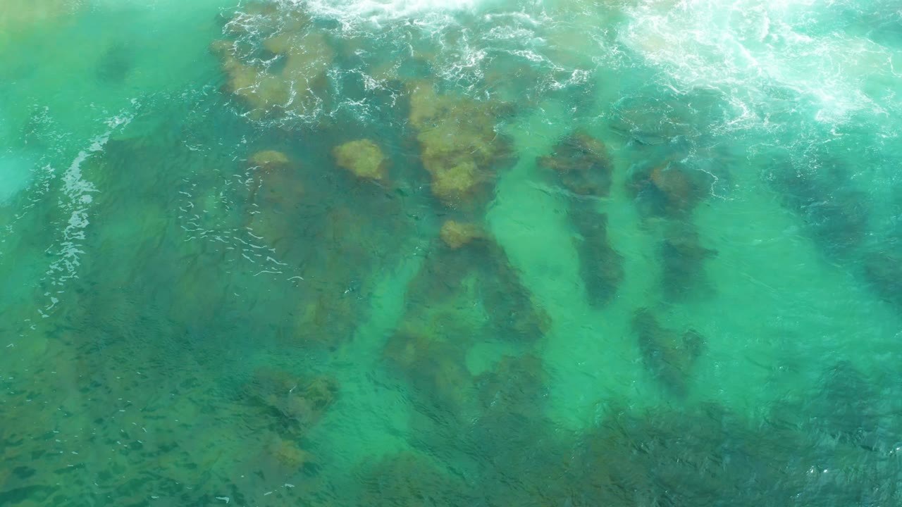 Turquoise water covers irregular brown rock clusters below the surface.