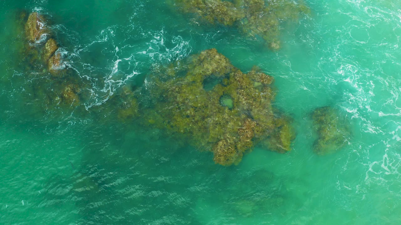 Overhead view of turquoise water and submerged reef at Laguna Beach, Baja California Sur, Mexico, with small ripples and no visible people.