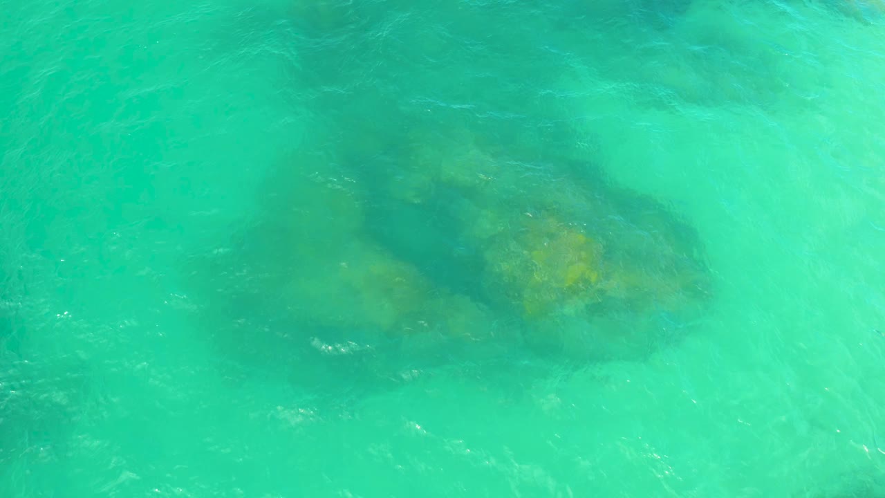 Turquoise water over submerged coastal rocks.