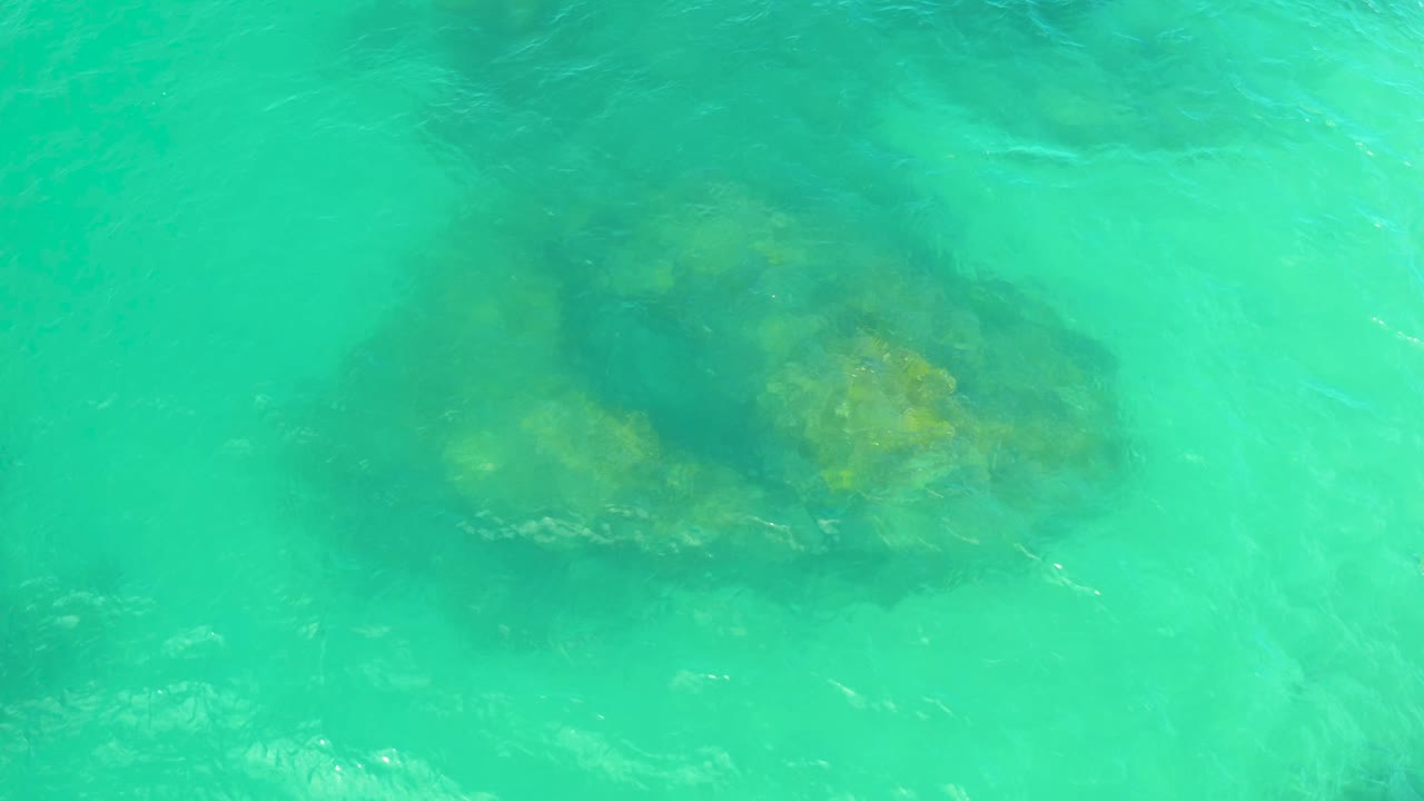 Teal water ripples across a partly shadowed underwater boulder in Laguna Beach, Baja California Sur, with no visible people.