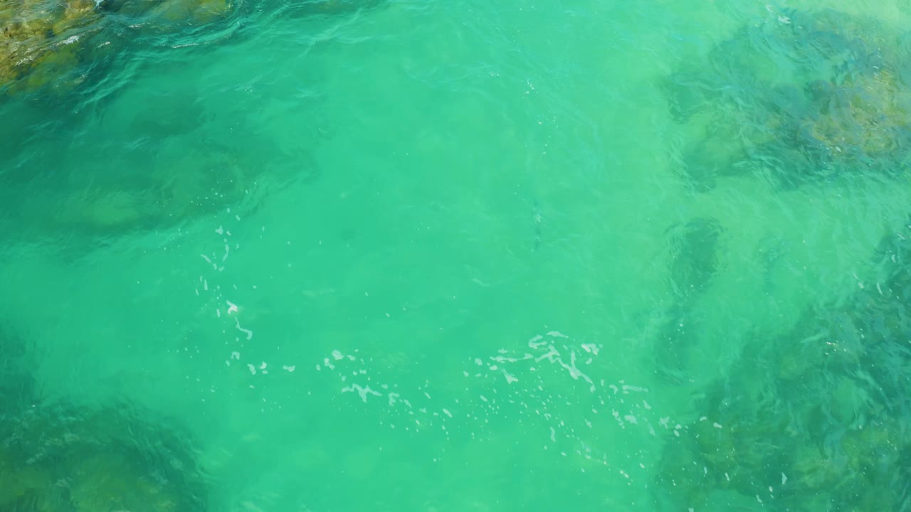 Clear blue-green water with shadowed rock below
