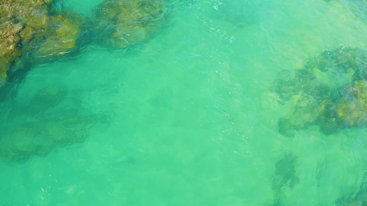 Overhead view of turquoise water and submerged rocks at Laguna Beach, Baja California Sur, with no visible people.