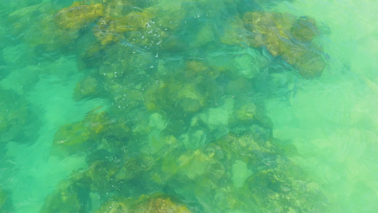 Shallow turquoise water ripples over uneven rocks near the center of the frame in Laguna Beach, Baja California Sur, with no visible people.