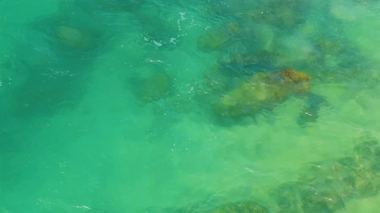 Clear green-blue water with rocks below