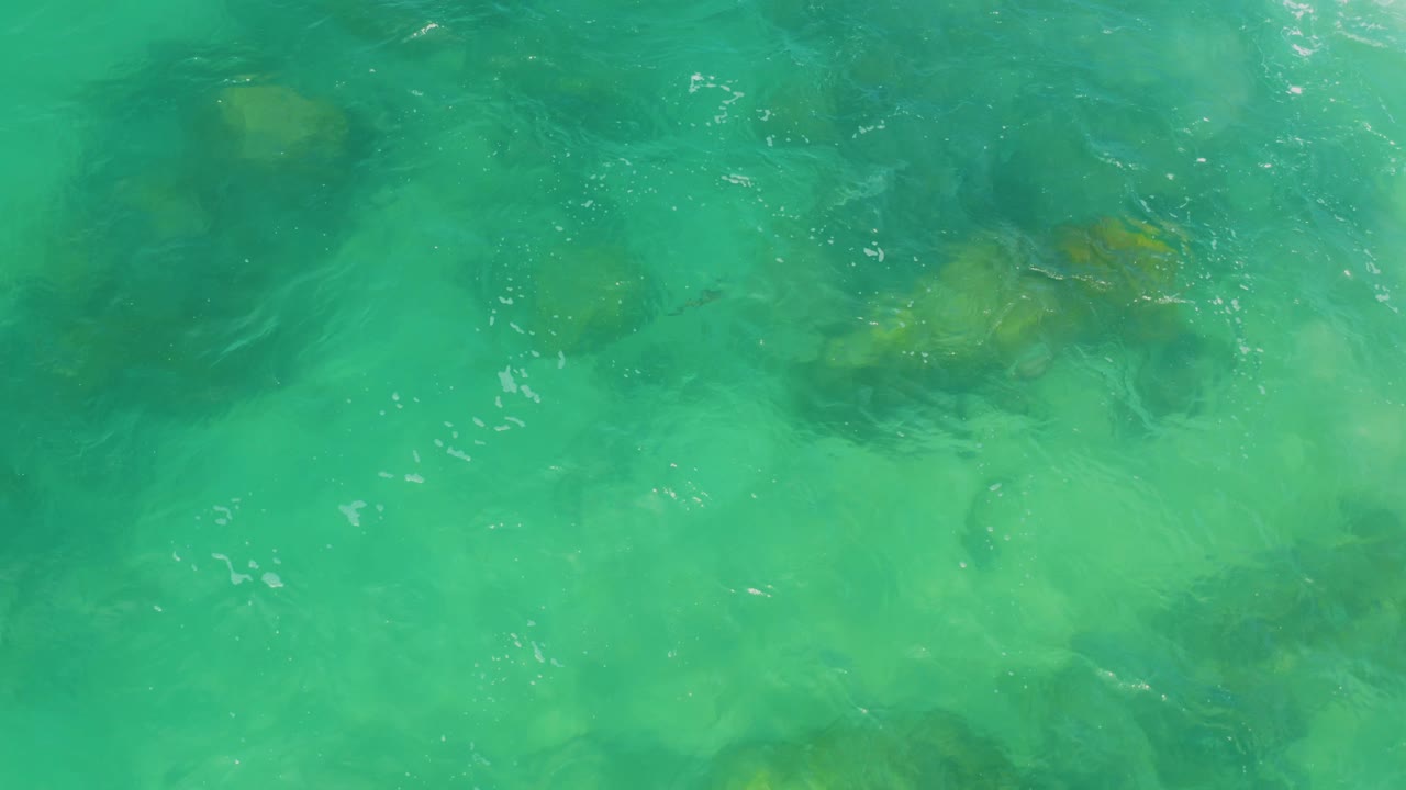 Clear turquoise water reveals shallow rock patches near the top of the frame at Laguna Beach, Baja California Sur, with no visible people.