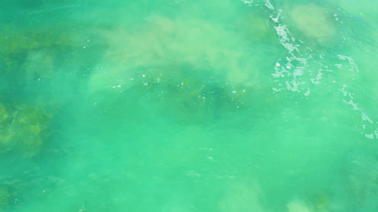 Bright turquoise water and faint submerged rock contours fill the frame at Laguna Beach, Baja California Sur, with no visible people.