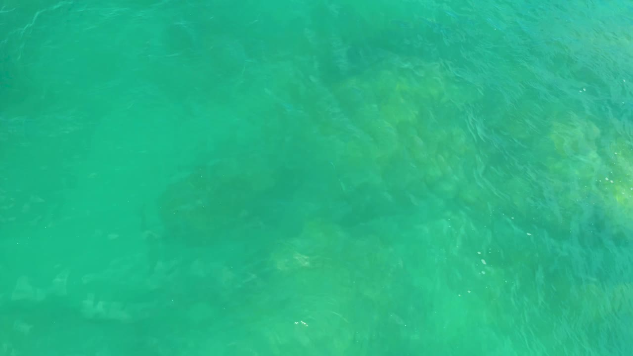Turquoise-green water covers darker reef shapes below the surface in Laguna Beach, Baja California Sur, with no visible people.