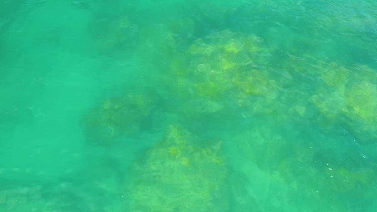 Green-blue rippling water covers pale rocks beneath the surface in Laguna Beach, Baja California Sur, with no visible people.