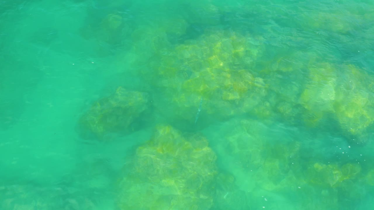 An overhead water plate shows broad submerged rocky forms under teal ocean color at Laguna Beach, Baja California Sur, with no visible people.