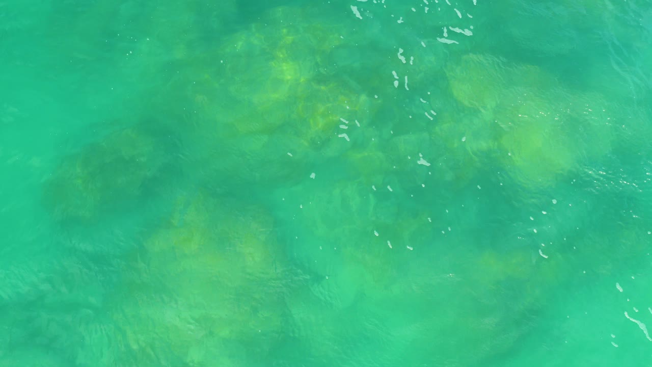 Overhead view of green ocean water in Laguna Beach, Baja California Sur, with soft surface ripples and no visible people.