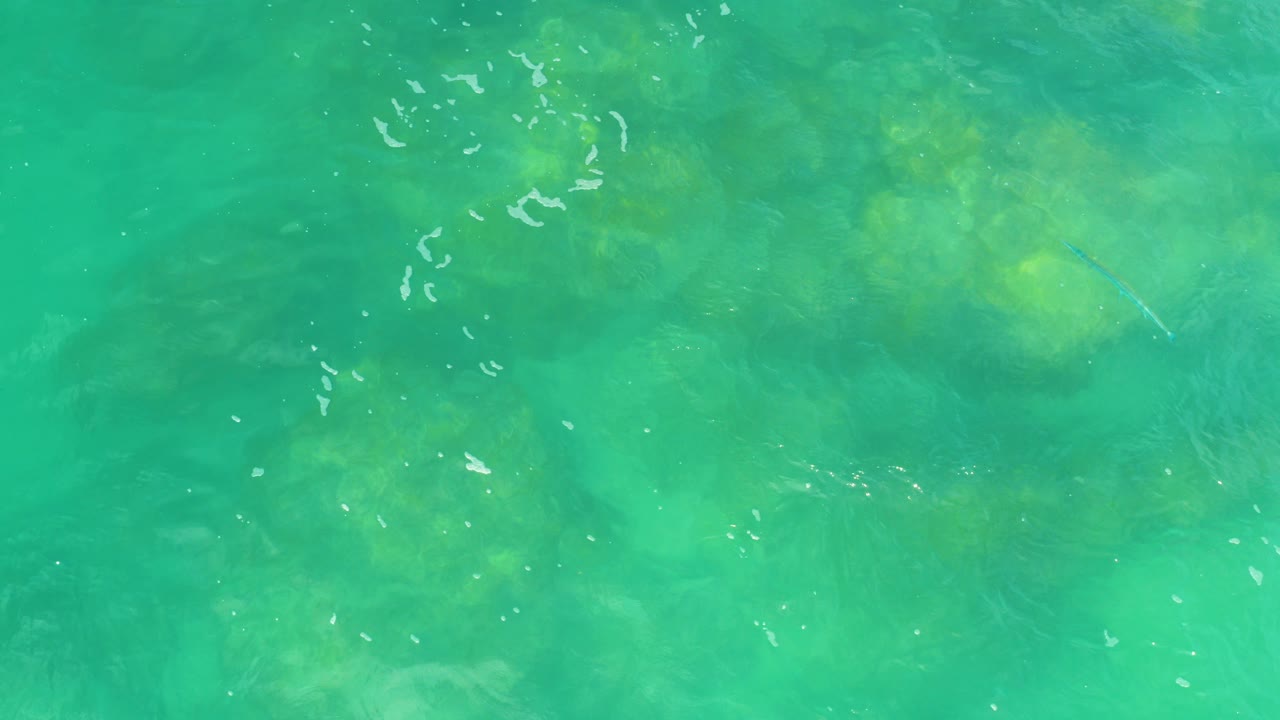 Turquoise seawater over submerged rock and plant patches.