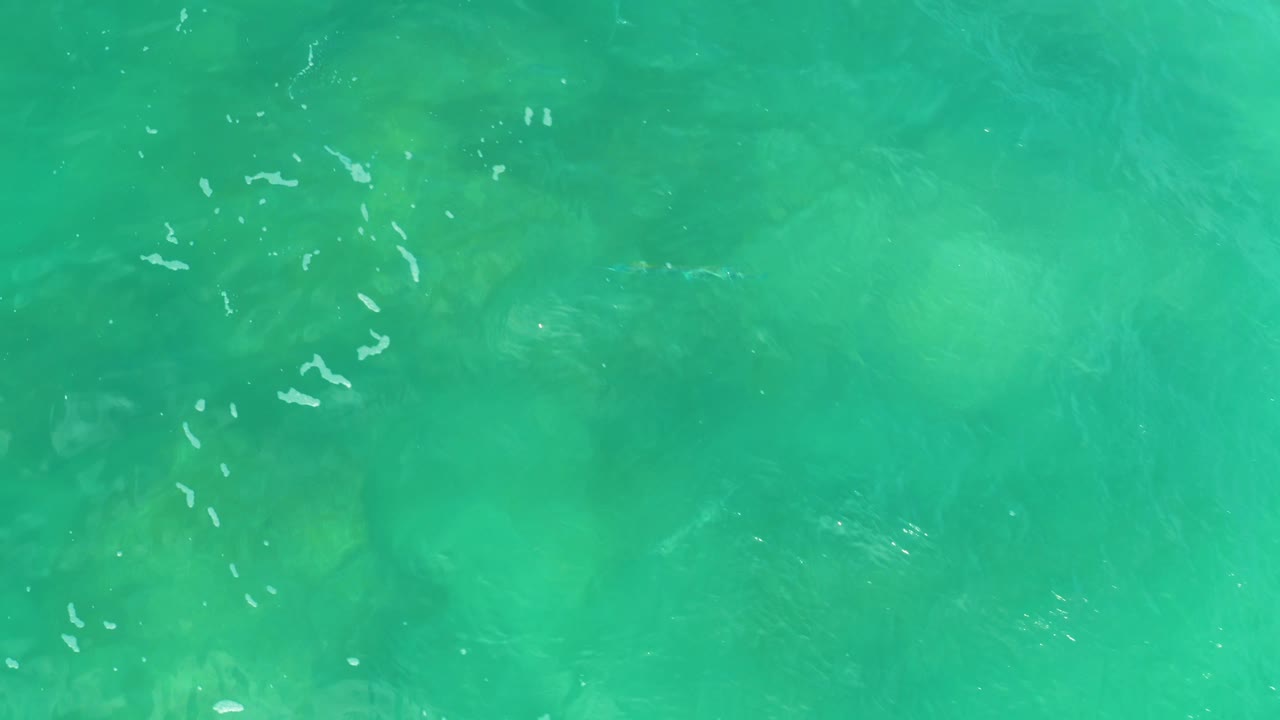 Turquoise-green ocean surface at Laguna Beach, Baja California Sur, with cloudy underwater formations, small white ripples, and no visible people.