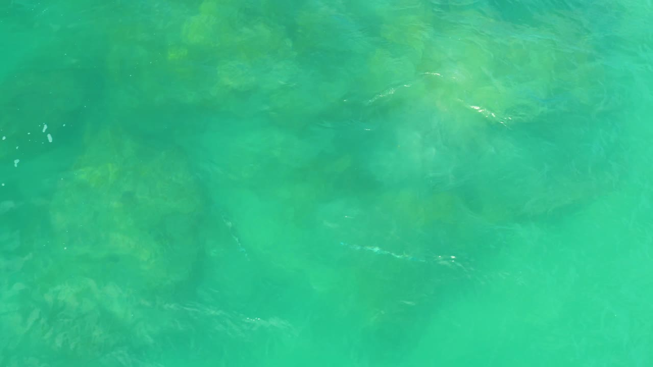 Turquoise coastal water reveals darker submerged rock forms at Laguna Beach, Baja California Sur, with no visible people.