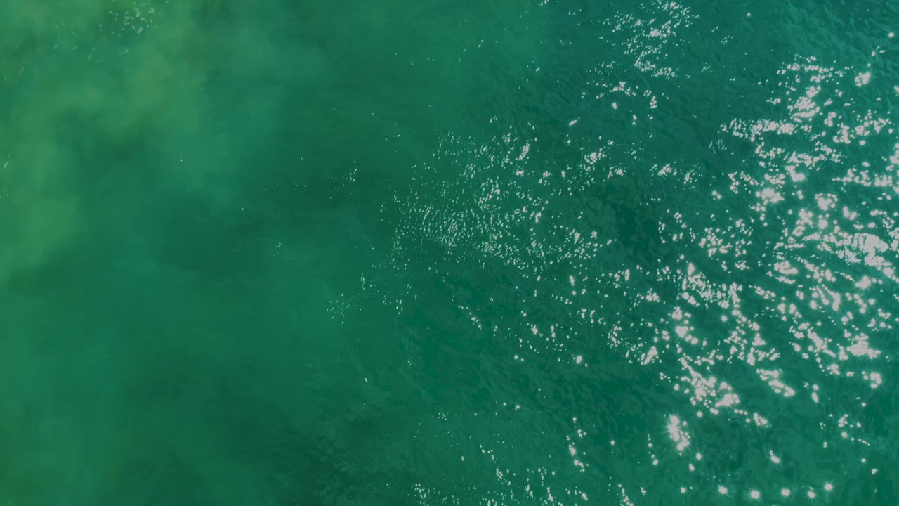 Overhead view of green-blue rippled water at Laguna Beach, Baja California Sur, with bright surface reflections and no visible people.