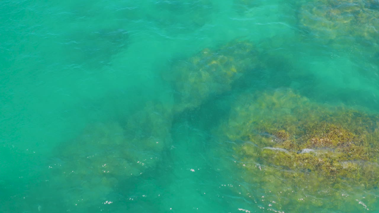 Overhead green lagoon water with submerged rocks.