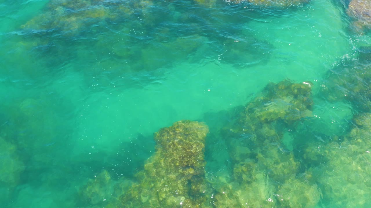 Aqua shallow water spreads over darker rock patches near the lower and right edges in Laguna Beach, Baja California Sur, with no visible people.