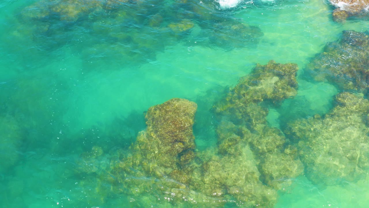 Overhead view of turquoise water in Laguna Beach, Baja California Sur, Mexico, with submerged rock formations visible through the clear surface and no visible people.