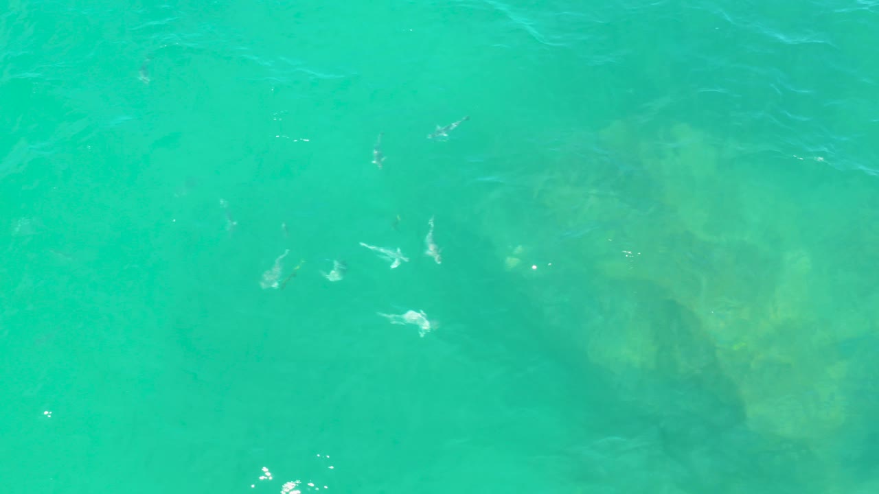 Overhead view of turquoise water in Laguna Beach, Baja California Sur, with hazy submerged rock forms and scattered white surface ripples, no visible people.