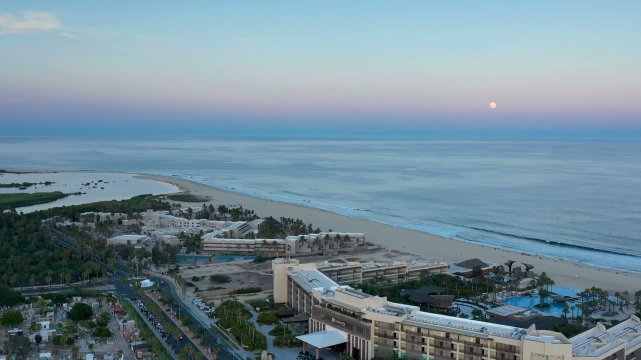Second frame shows the San Jose del Cabo beach and ocean from above, with the resort complex shifted slightly across the lower frame, long surf lines, pastel dusk sky, and no visible people.