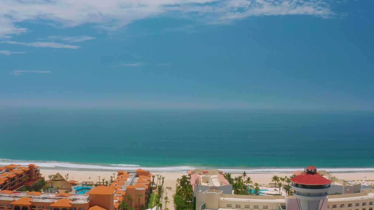 Beachfront resort foreground beneath wide blue ocean and sky.