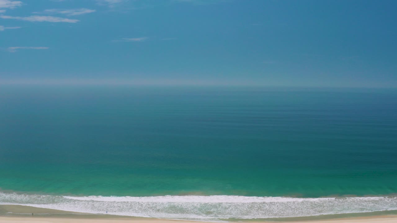Blue ocean horizon above a thin surf line and sandy beach.
