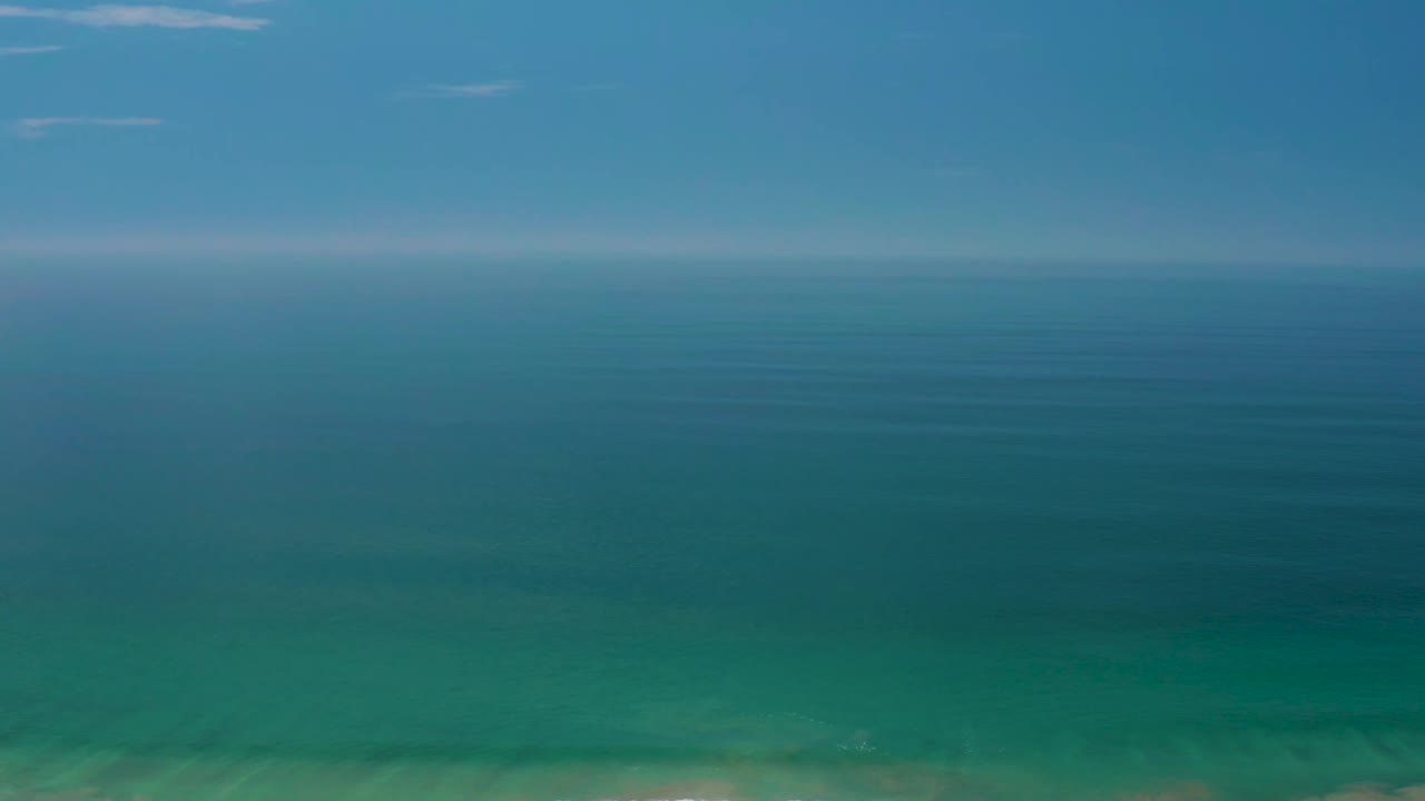 Palmilla Beach open-water frame with darker blue ocean in the middle distance, soft haze along the horizon, and no visible people.