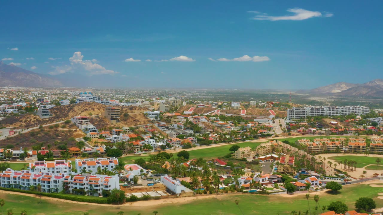 Aerial view across Palmilla Beach buildings, lawns, roads, hills, and mountains.