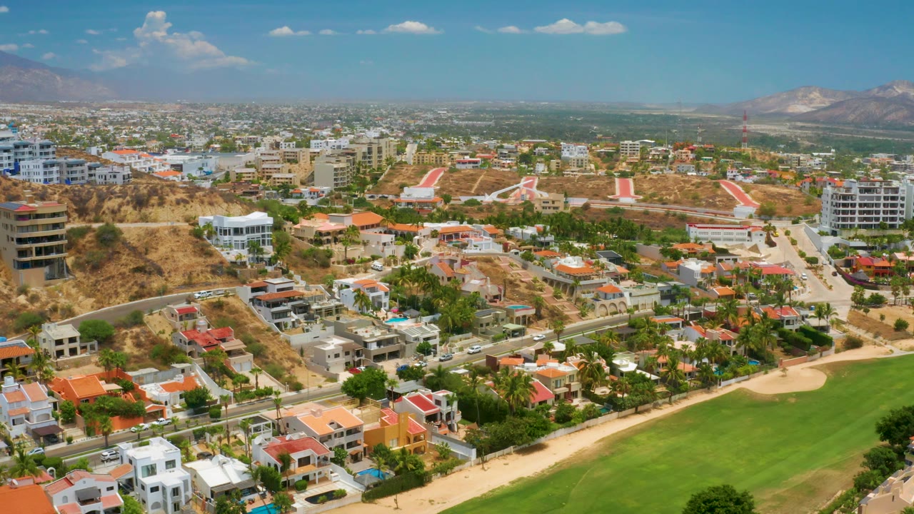 Aerial view across a hillside residential area and green fairway-like field