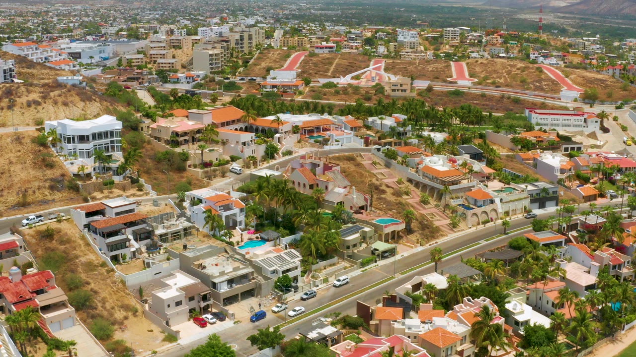 Elevated view across luxury homes, turquoise pools, palms, and dry lots.
