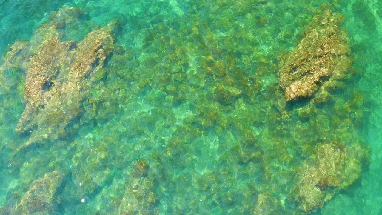 A larger submerged rock sits under clear coastal water at Palmilla Beach, Baja California Sur, with sunlit ripples and no visible people.