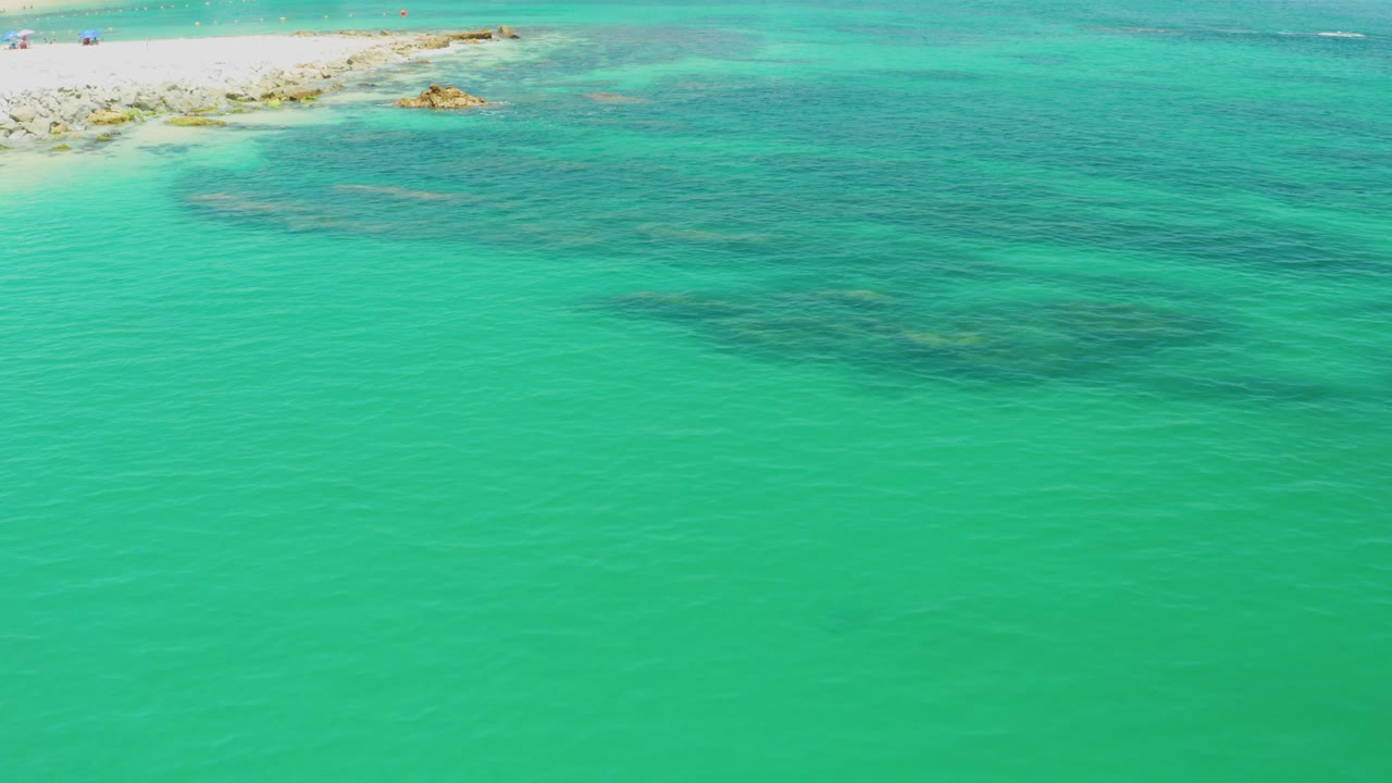 Turquoise shallow ocean beside a pale rocky beach edge.