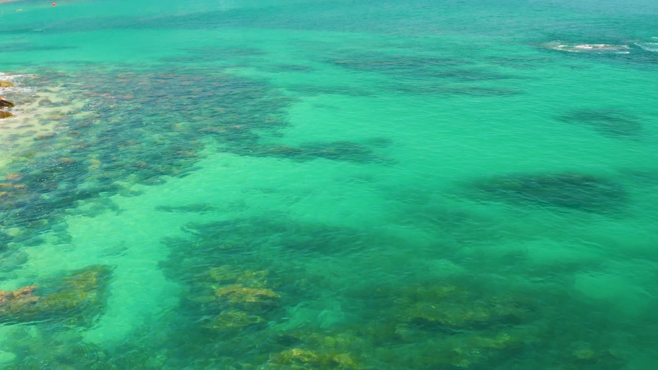 Clear green-blue water with submerged rock texture.