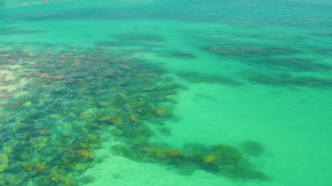 Rocky underwater shelf beside open turquoise water.