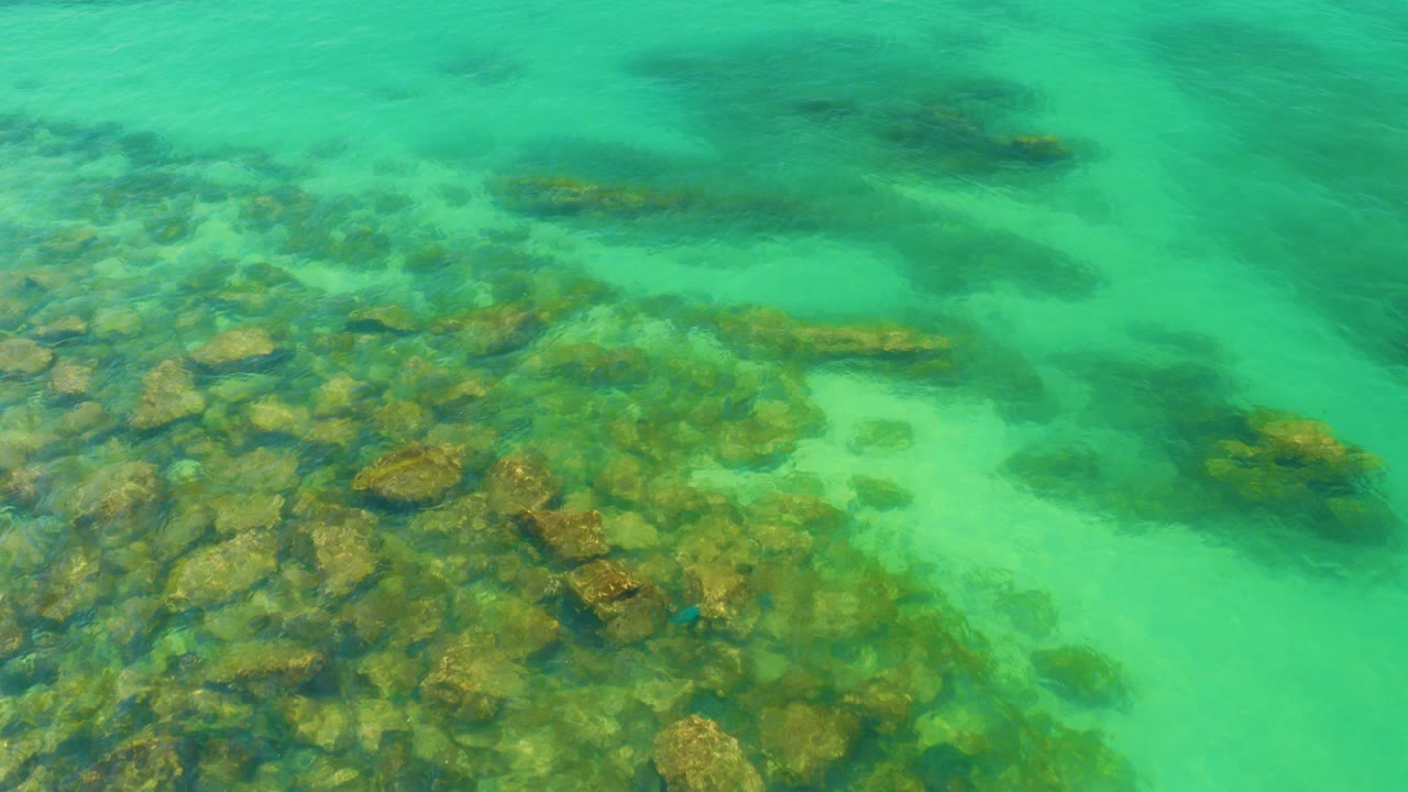 Overhead view of turquoise water and submerged rocks at Palmilla Beach, Baja California Sur, with no visible people.