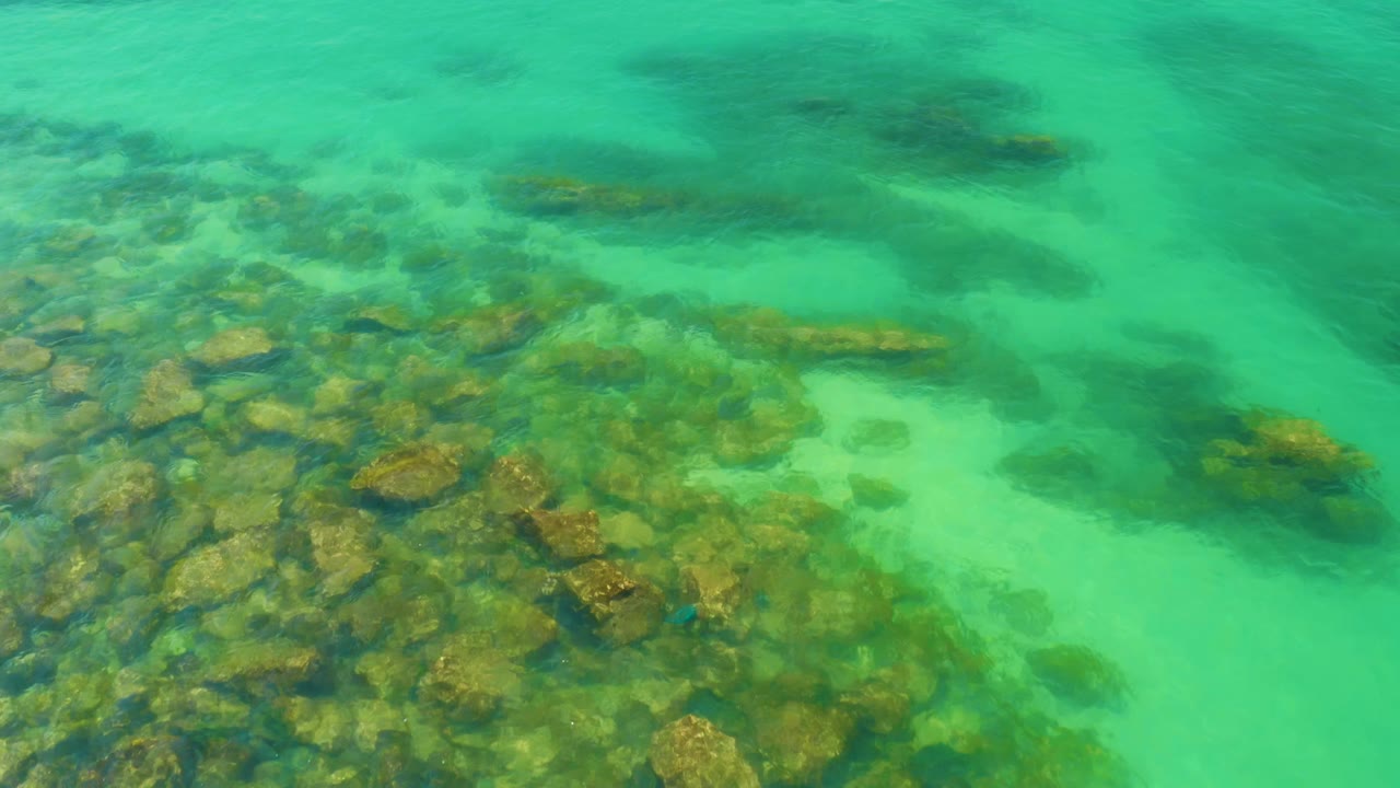 Green ocean water moving over brown rocks.