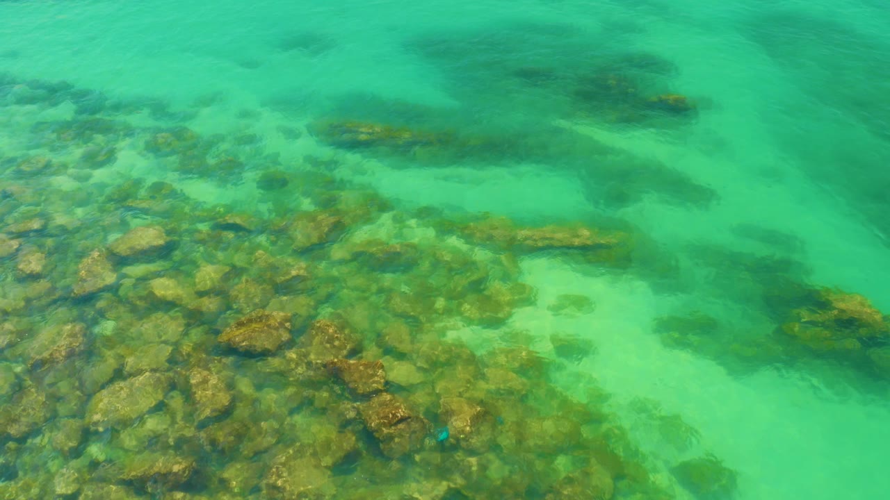 Aerial-looking frame of clear green water over scattered rocks at Palmilla Beach, Baja California Sur, with no horizon and no visible people.