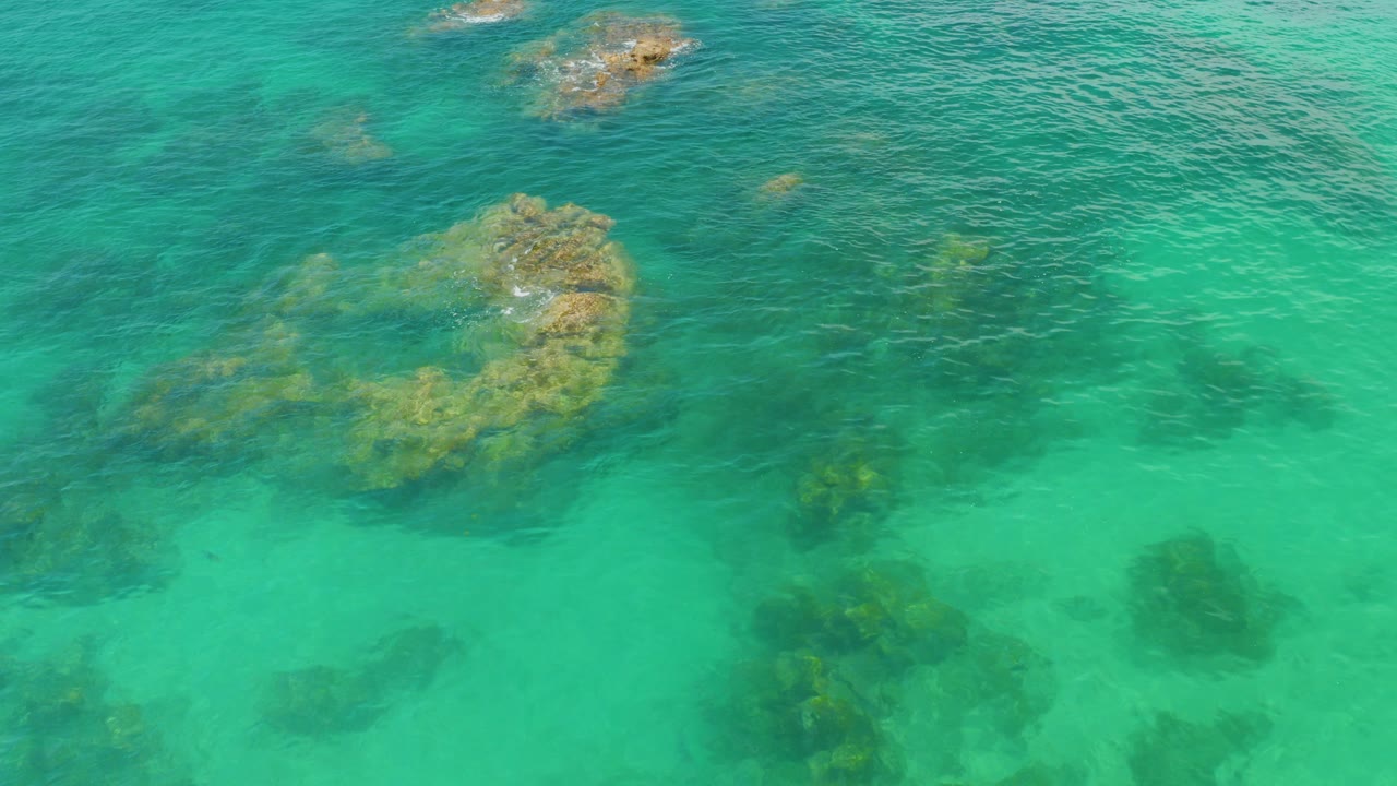 Overhead view of turquoise water at Palmilla Beach, Baja California Sur, with submerged rock clusters and no visible people.