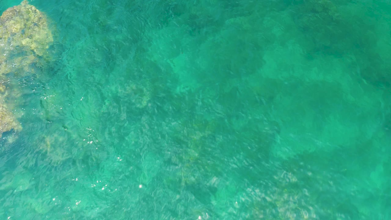 Turquoise water with rock formations along the left side.
