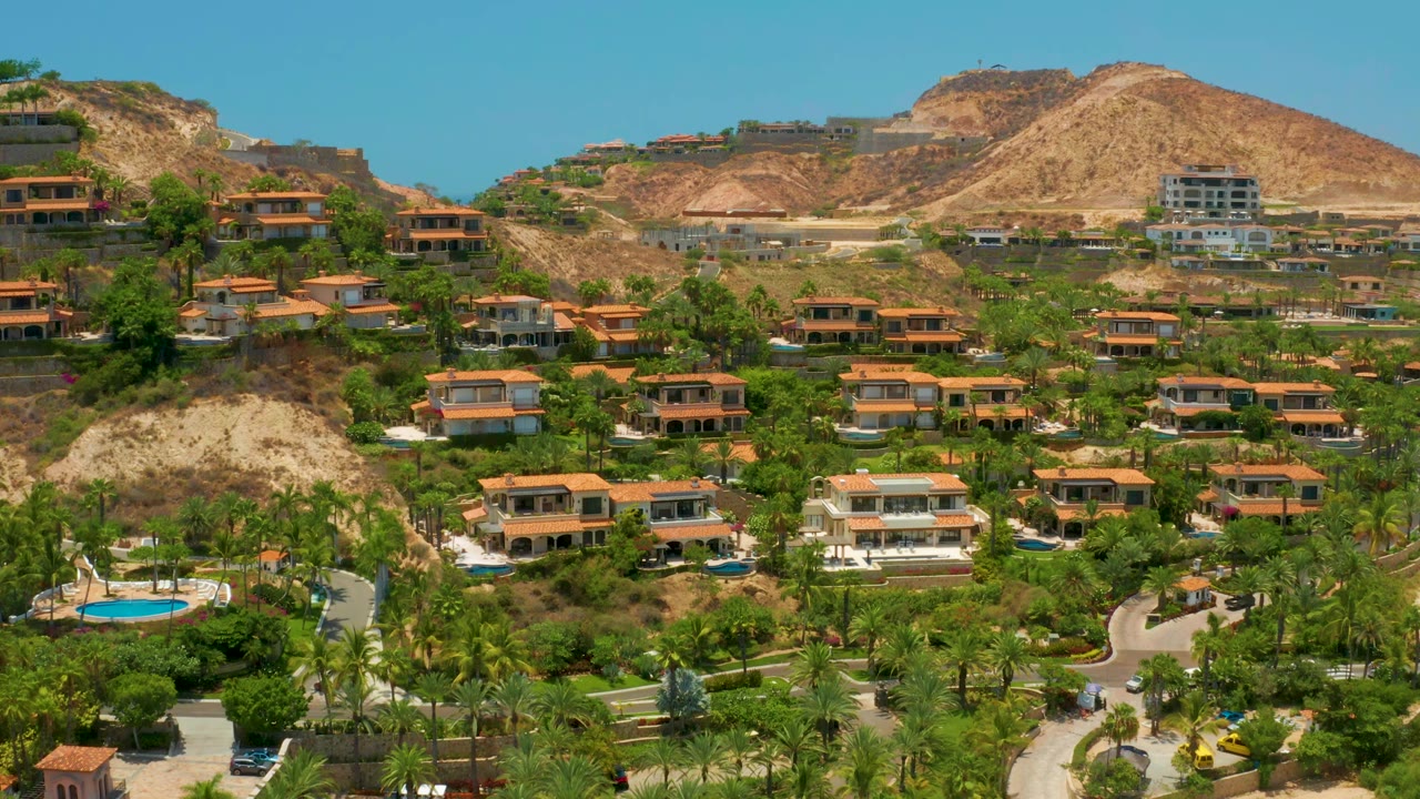 Palmilla Beach hillside view with resort-style houses spread across green landscaping, tan ridges in back, and no visible people in the frame.
