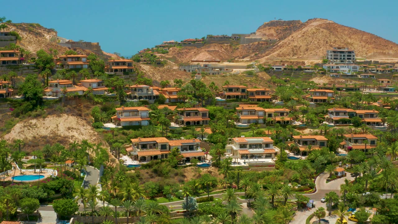 Palm-lined hillside homes with pools and dry mountainside