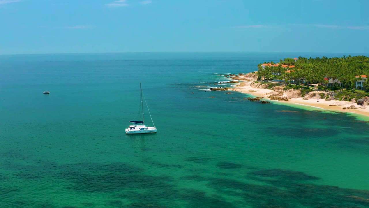 Sailboat centered on green water with coast in the background.
