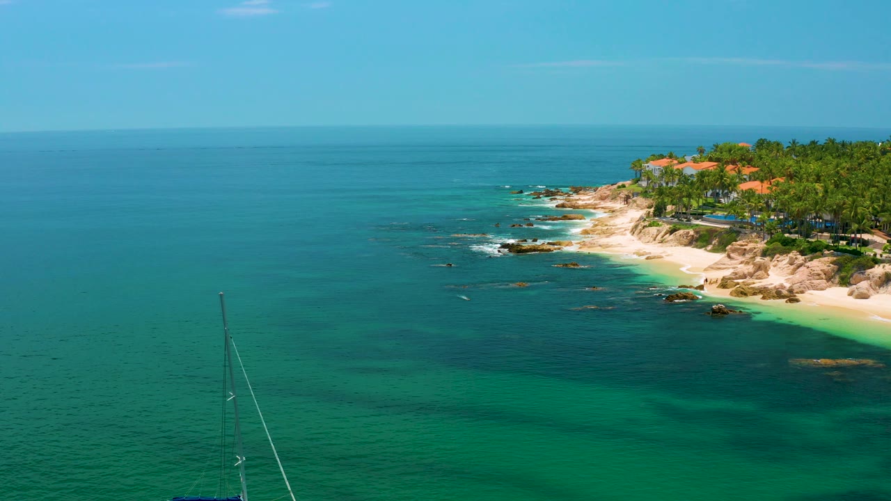 Sailboat mast at lower left with Palmilla Beach shoreline across the upper right.