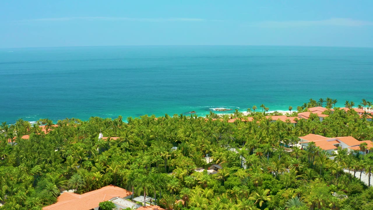 Open blue water above a green palm-lined coast with orange rooftops.