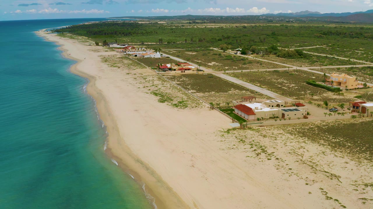 High coastal view with sea, sand, houses, roads, and scrubland