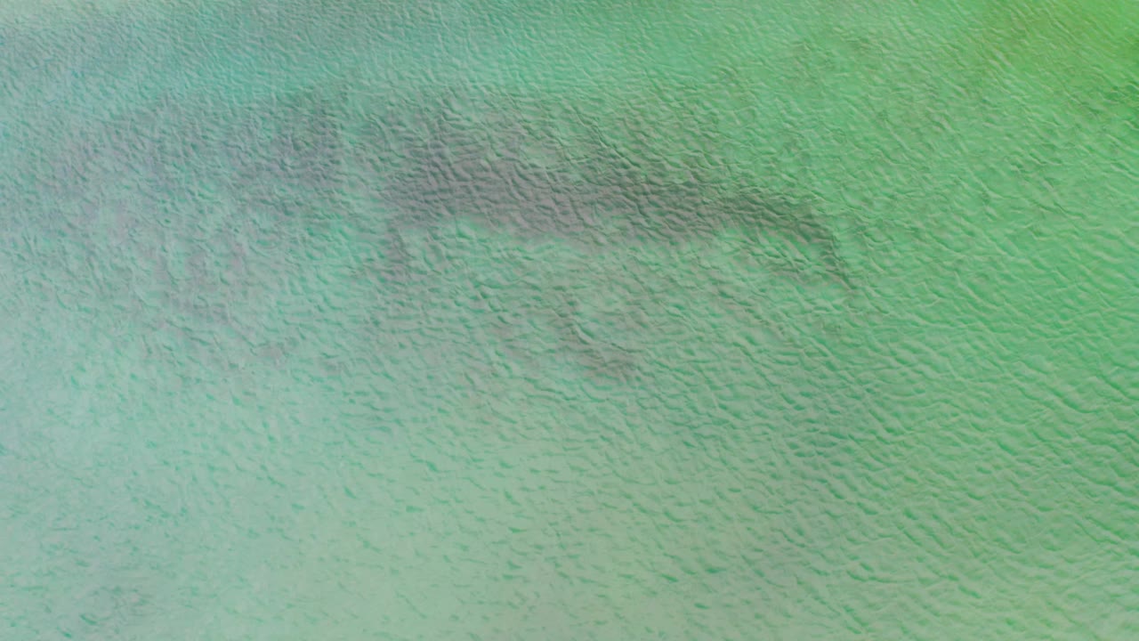 Top-down La Ribera ocean frame with blue-green color, fine surface texture, faint darker bands, and no visible people.