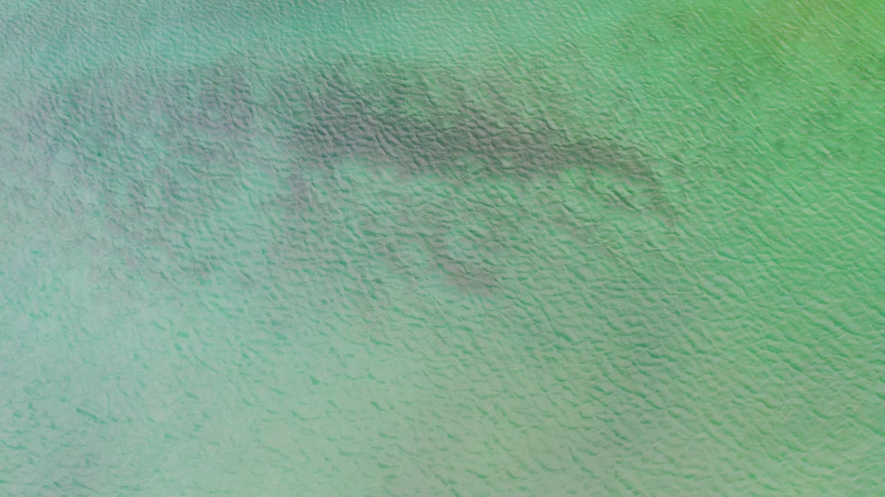 Aerial view of muted turquoise La Ribera water with a darker band crossing the upper portion and no visible people.
