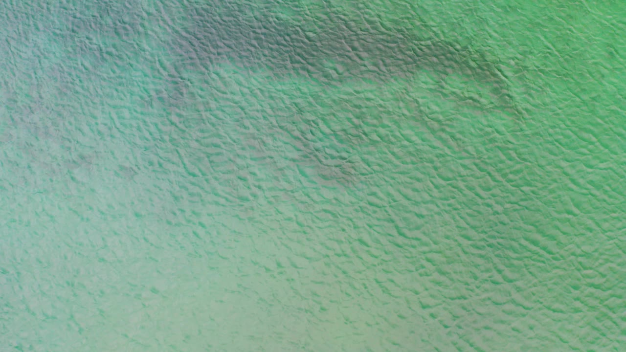 Overhead view of turquoise-green ocean surface in La Ribera, Baja California Sur, with fine ripples and no visible people.