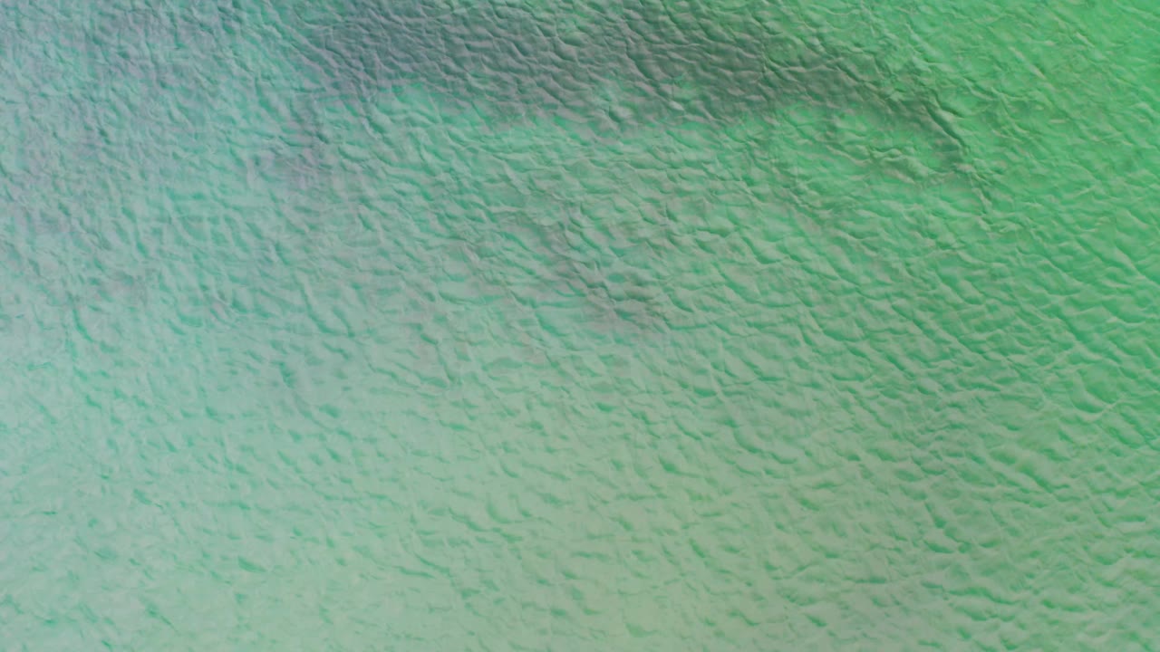 Overhead La Ribera ocean surface with pale turquoise water, faint wave marks, and no visible people or land in the frame.