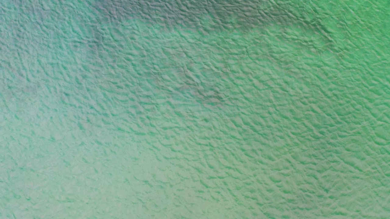 Aerial view of La Ribera saltwater with green ripples, lighter turquoise patches, and no visible people, boats, or shoreline.