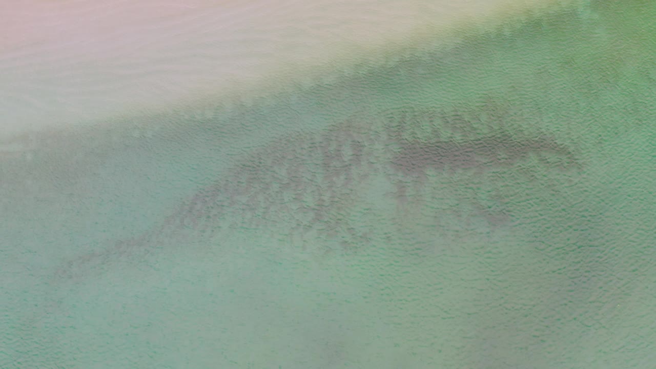 At 0:02, turquoise water dominates the La Ribera frame while a darker patch sits closer to the upper right, and no people are visible.